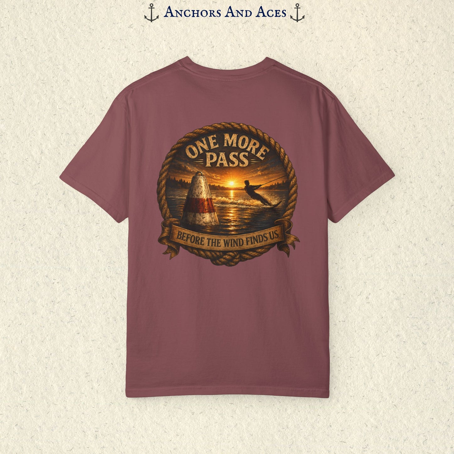 Brick red vintage slalom water ski T-shirt shown from the back with a sunrise lake graphic featuring a slalom buoy, water skier, rope border, and the text One More Pass and Before the Wind Finds Us.