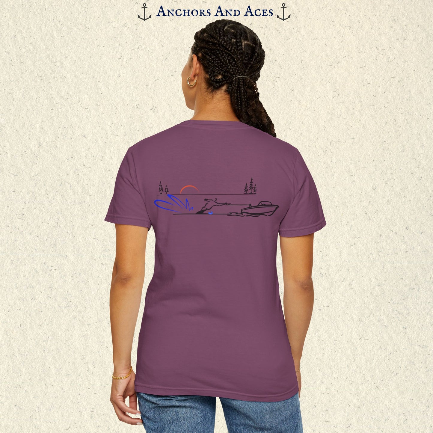 Model wearing a Berry Comfort Colors 1717 water ski t-shirt from the back, featuring minimalist line art of a ski boat pulling a slalom water skier at sunrise with pine trees and blue spray.