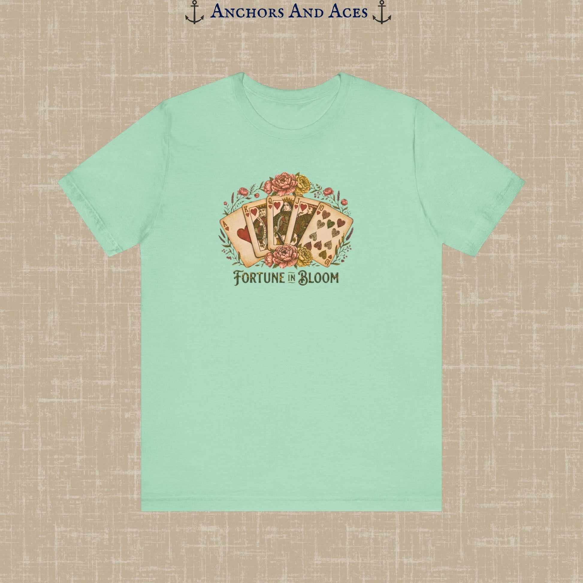  A light green t-shirt featuring a floral design with playing cards. The graphic includes the text "Fortune in Bloom" below the cards. The shirt is a short-sleeved crew neck.