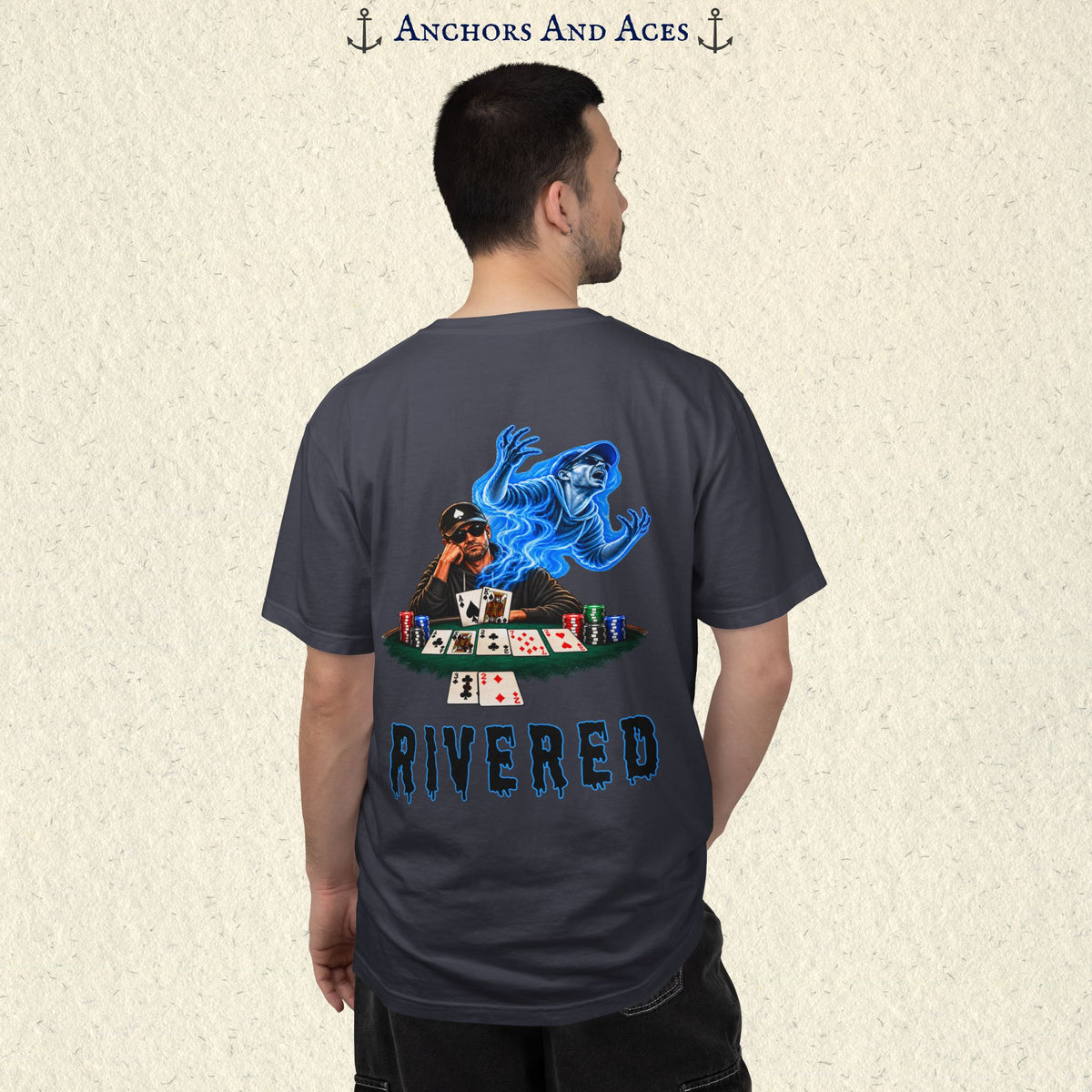 Model wearing RIVERED Texas Hold'em poker graphic tee back view featuring a player at a poker table with playing cards, poker chips, and an electric blue soul rising from his body after a bad beat on the river.  Comfort Colors 1717