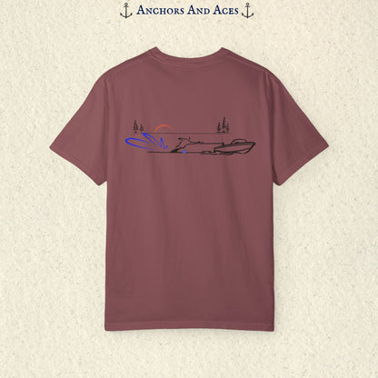 Berry Comfort Colors 1717 water ski shirt shown from the back, featuring minimalist line art of a ski boat pulling a slalom water skier across calm lake water at sunrise with pine trees and blue spray.