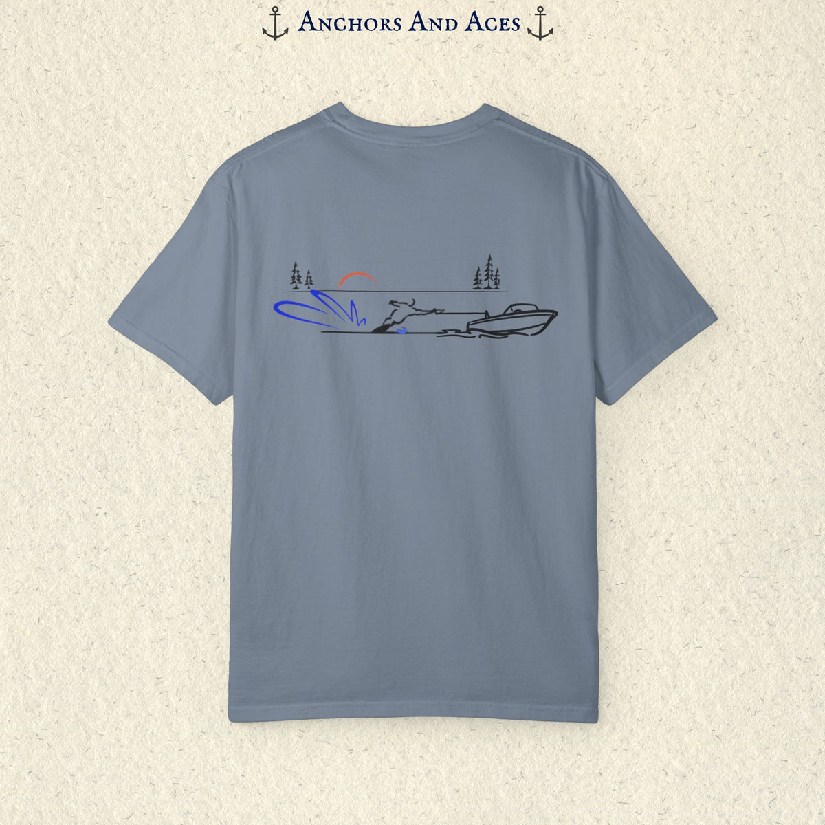 Blue Jean Comfort Colors 1717 water ski shirt shown from the back, featuring minimalist line art of a ski boat pulling a slalom water skier across calm lake water at sunrise with pine trees and blue spray.