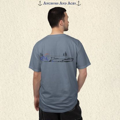 Model wearing a Blue Jean Comfort Colors 1717 water ski t-shirt from the back, featuring minimalist line art of a ski boat pulling a slalom water skier at sunrise with pine trees and blue spray.