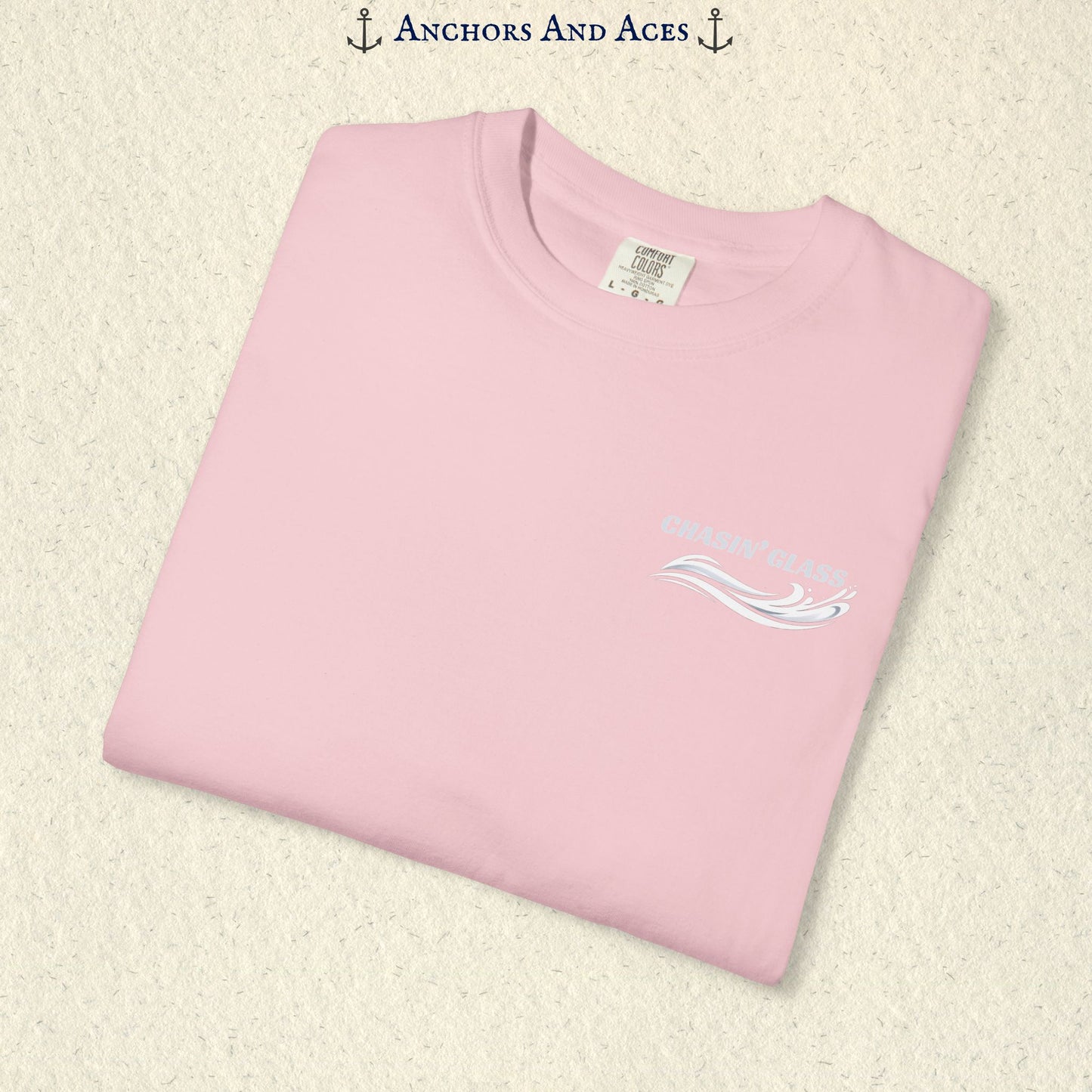 Folded Blossom Comfort Colors 1717 t-shirt showing the front left-chest Chasin' Glass logo, featuring white lettering above a stylized water-splash graphic.