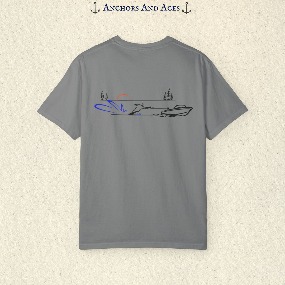 Grey Comfort Colors 1717 water ski shirt shown from the back, featuring minimalist line art of a ski boat pulling a slalom water skier across calm lake water at sunrise with pine trees and blue spray.