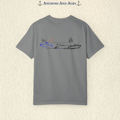 Grey Comfort Colors 1717 water ski shirt shown from the back, featuring minimalist line art of a ski boat pulling a slalom water skier across calm lake water at sunrise with pine trees and blue spray.