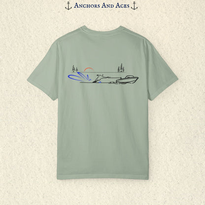 Bay Comfort Colors 1717 water ski shirt shown from the back, featuring minimalist line art of a ski boat pulling a slalom water skier across calm lake water at sunrise with pine trees and blue spray.