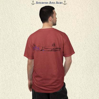 Model wearing a Crimson Comfort Colors 1717 water ski t-shirt from the back, featuring minimalist line art of a ski boat pulling a slalom water skier at sunrise with pine trees and blue spray.