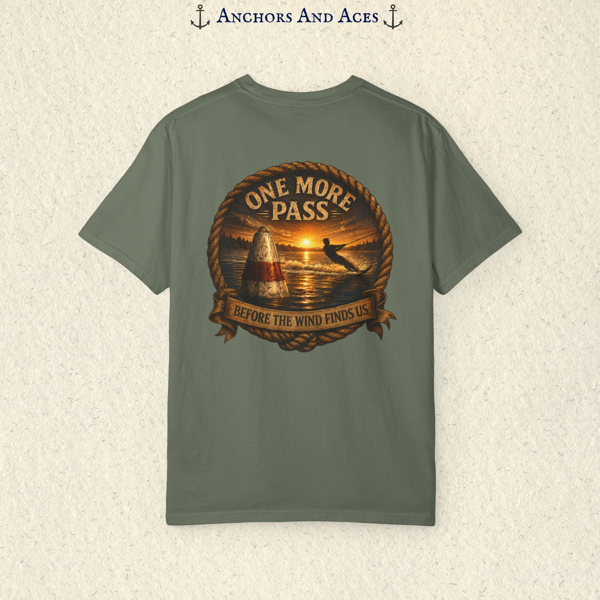 Moss green vintage slalom water ski T-shirt shown from the back with a sunrise lake graphic featuring a slalom buoy, water skier, rope border, and the text One More Pass and Before the Wind Finds Us.