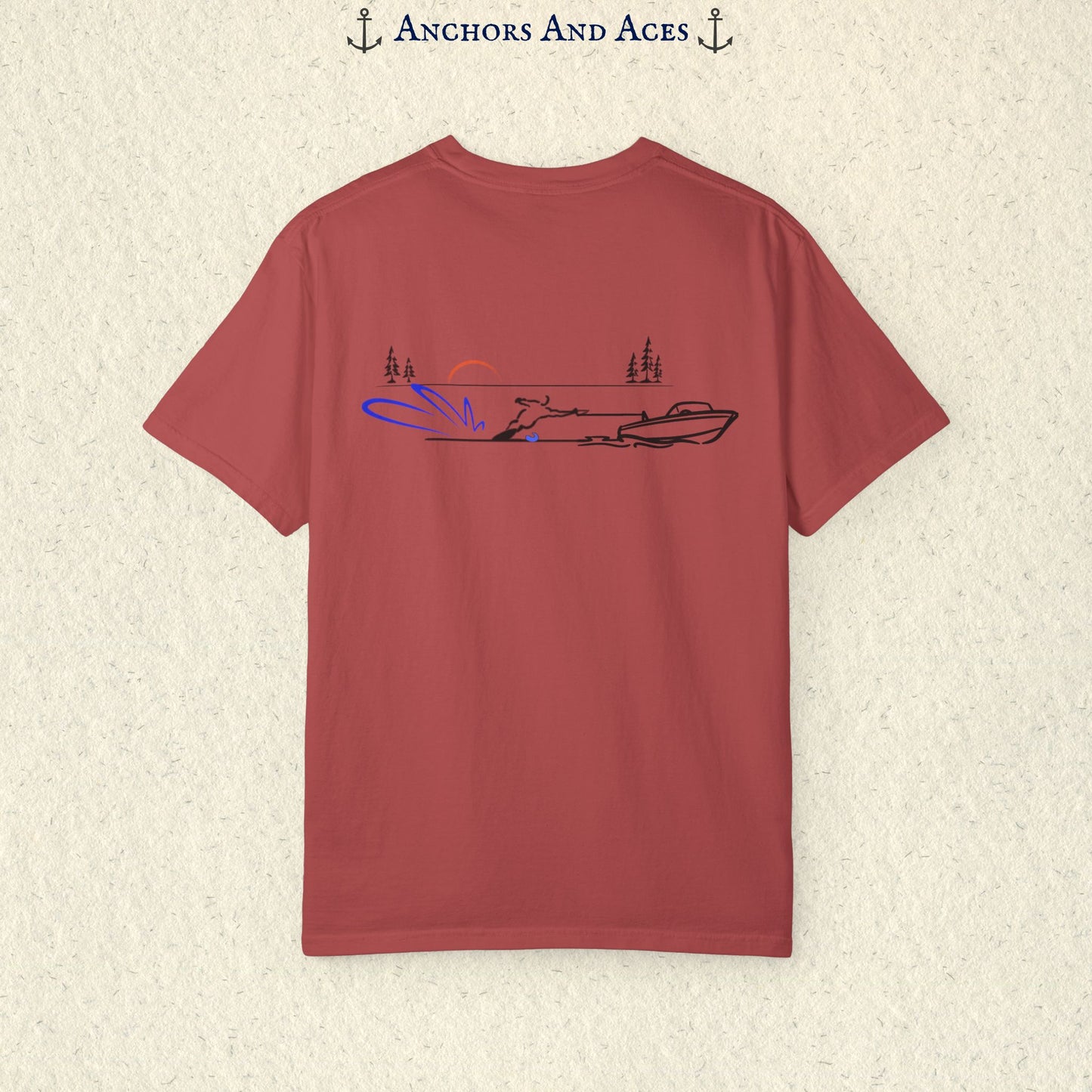 Crimson Comfort Colors 1717 water ski shirt shown from the back, featuring minimalist line art of a ski boat pulling a slalom water skier across calm lake water at sunrise with pine trees and blue spray.