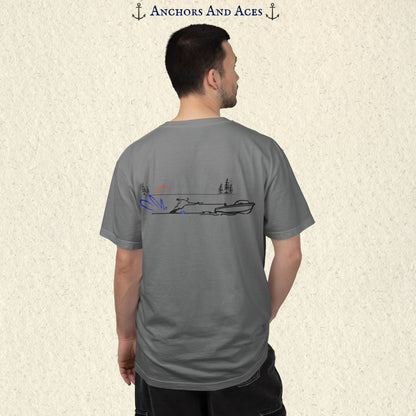 Model wearing a Grey Comfort Colors 1717 water ski t-shirt from the back, featuring minimalist line art of a ski boat pulling a slalom water skier at sunrise with pine trees and blue spray.