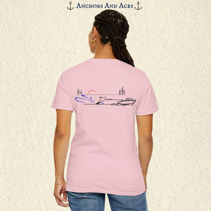 Model wearing a Blossom Comfort Colors 1717 water ski t-shirt from the back, featuring minimalist line art of a ski boat pulling a slalom water skier at sunrise with pine trees and blue spray.