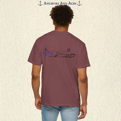 Model wearing a Brick Comfort Colors 1717 water ski t-shirt from the back, featuring minimalist line art of a ski boat pulling a slalom water skier at sunrise with pine trees and blue spray.