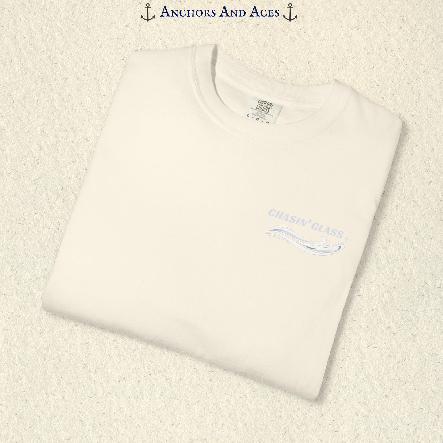 Folded Ivory Comfort Colors 1717 t-shirt showing the front left-chest Chasin' Glass logo, featuring white lettering above a stylized water-splash graphic.